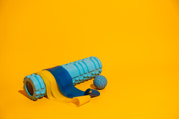 Foam roller with resistance bands and massage ball on vivid yellow background wellness recovery copy space. High quality photo