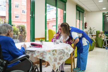 Caregiver assisting and comforting an elderly woman during an activity in a senior living facility, promoting connection and well being