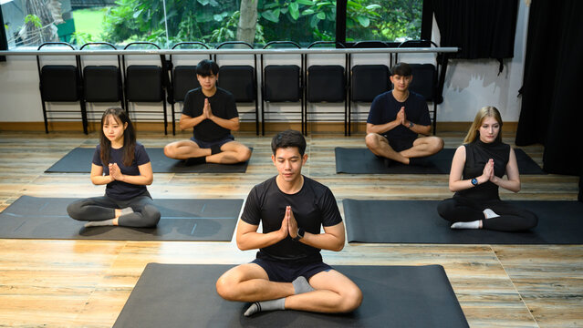 People in meditation posture during group yoga session, focusing on relaxation and balance