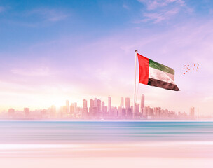 United Arab Emirates flag wavering in front of scenic view of modern skyline.