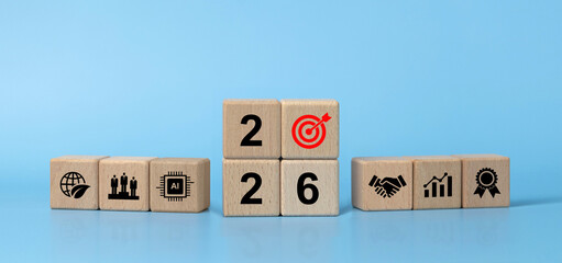 Wooden blocks 2026 with a red target icon, flanked by symbols for AI, sustainability, teamwork, partnership, growth and quality, illustrating business goals, strategy, KPI and roadmap for the new year