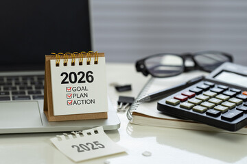 Obraz na płótnie Canvas Desk calendar 2026 with checklist Goal, Plan, Action on office workspace beside calculator, notebook, pen and laptop, represent financial planning, budget, KPI targets and execution for the new year
