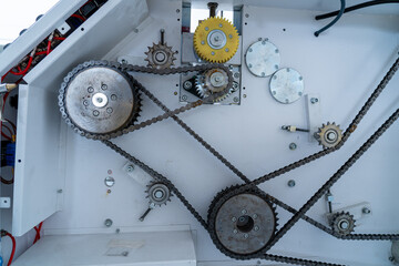 Industrial chain drive mechanism with metal sprockets and yellow gear, closeup