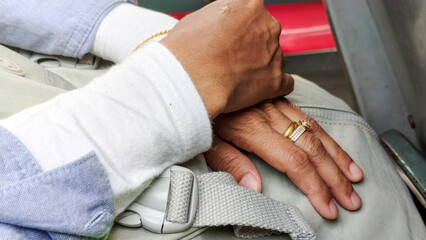 Close Up of Hands with Gold Rings Resting on Lap with Seat Belt