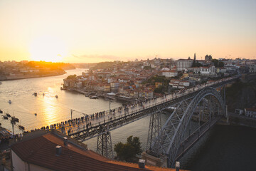 Porto cityscape at sunset over the douro river with the iconic dom luis i bridge packed with people enjoying golden hour light, waterfront reflections and historic skyline