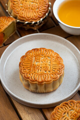 Close up of traditional mooncake in wooden basket with cup of tea in background, it's often eat during celebrating the Mid-Autumn Festival. Chinese character represent "Gold medal mooncake"