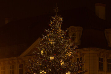Christmas tree illuminated with lights at night, showing glowing decorations and festive atmosphere in a dark seasonal setting. Lifestyle