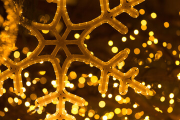 Glowing decorative snowflake in close up, used as a Christmas background element with festive illumination.