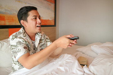 Men with the remote control front of the television. A man is relaxing on sofa and watching sports on TV.