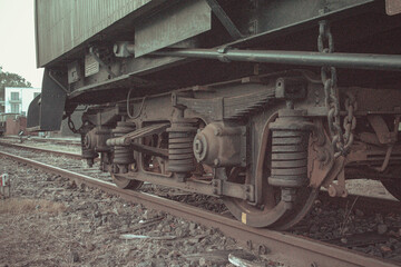 Detailed photo of vintage train undercarriage with suspension system and rusty track