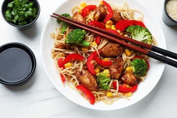 Delicious noodles with meat and vegetables served on white marble table, flat lay