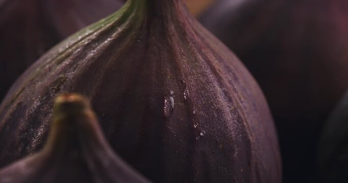 Slow Motion Close Up of Fresh Ripe Fig with Water Drop Sliding on Dark Purple Skin. Juicy Exotic Fruit Macro Shot Highlighting Freshness and Natural Sweetness  at 1000 fps.