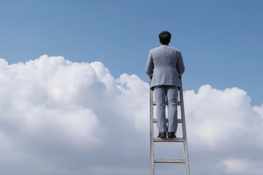 Businessman climbing ladder towards success against blue sky and clouds