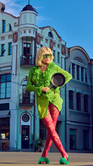 Stylish woman in green dress holding frying pan with bold attitude on urban street. Concept of surreal fashion editorial, lifestyle branding, digital marketing, modern art visuals.