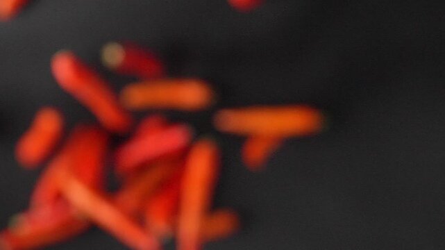 Slow motion shot of fresh Datil peppers flying towards camera on black background. Premium hot pepper footage perfect for food commercials and spicy culinary content.
