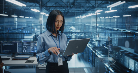 Smiling Asian Female Data Center Specialist Analyzes Server Performance on a Laptop, Optimizing Network Efficiency in a High-tech Environment. Developer Manages Cybersecurity and System Reliability