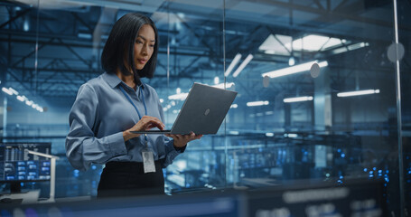 Portrait of a Asian Female Data Center Specialist Analyzing System Performance on a Laptop, Optimizing Cybersecurity Protocols in a High-tech Facility. Developer Monitors Real-time Data on Computer