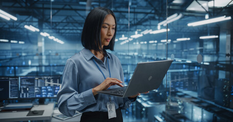Portrait of a Asian Female Data Center Specialist Analyzing System Performance on a Laptop, Optimizing Cybersecurity Protocols in a High-tech Facility. Developer Monitors Real-time Data on Computer