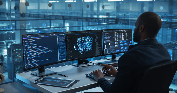 With Multiple Screens Open to Code and Analyze Neural Network Visualizations, African Software Developer in a Data Center Refines an AI Algorithm, Working Methodically to Improve the Product