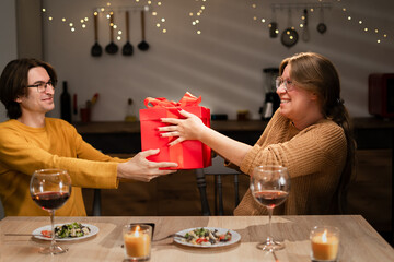 Valentine's Day concept. Happy couple in love celebrating Valentine's Day at home. Man give gift to his wife