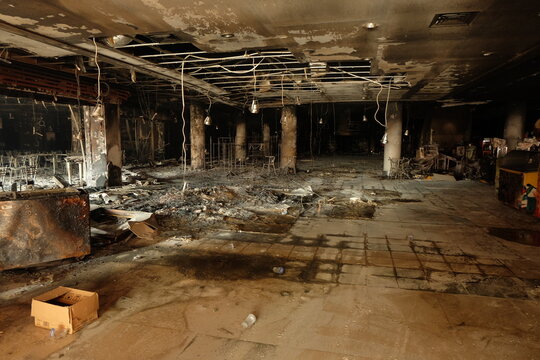 Burnt interior shows devastation after fire in commercial building, revealing charred debris and structural damage with somber atmosphere.