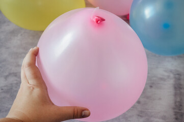 Hand holding a bunch of colorful inflated balloons in pastel shades of pink, yellow, green, and blue. Perfect for birthday parties, festive events, or holiday celebrations.