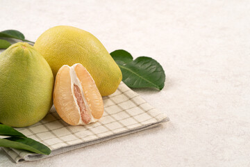 Fresh pomelo fruit with leaf on white table background.
