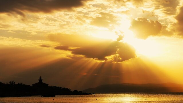 Lighthouse in magnificent golden sunset with powerful sun and rays and light