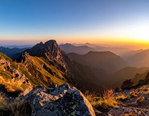 Golden hour sunset illuminates a vast mountain range, viewed from a rocky peak with sparse vegetation