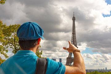 Turista disfrutando de la Torre Eiffel en París, con boina azul parisina y sonrisa alegre. © ismel leal
