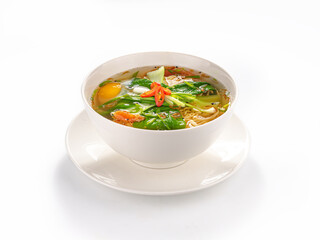 Asian noodle soup with egg, vegetables and herbs in white bowl