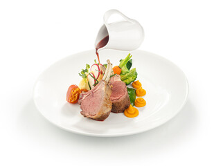 Rack of lamb with vegetables and sauce on white plate