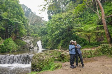 Obraz premium Adventures Friends Capture Stunning Waterfall Beauty Amidst Lush Tropical Rainforest Exploration