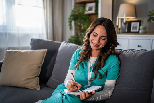 Smiling nurse writing notes during a home visit