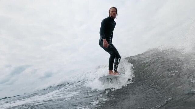 Surfer skillfully rides a wave, showcasing balance and control in dynamic ocean scene