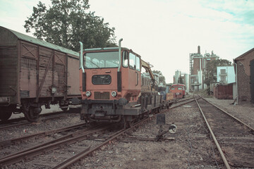 Obraz premium Red industrial railway maintenance vehicle on tracks near old freight wagons