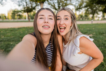 Obraz premium Mother and teenage daughter taking a selfie in park