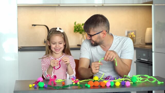 Father and little daughter make diy from colored chenille wire. Happy family create handmade craft. Leisure. Education