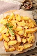 Tasty baked potatoes with rosemary and peppercorns on wooden table, flat lay