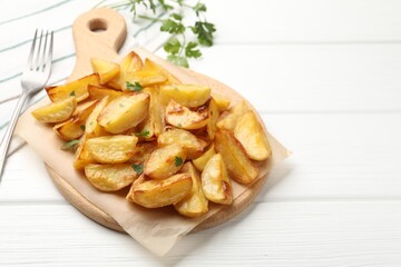 Tasty baked potatoes with parsley on white wooden table, closeup. Space for text
