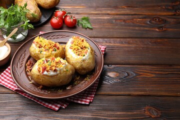 Tasty baked potatoes with sour cream, green onion, cheese and bacon on wooden table. Space for text