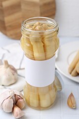 Pickled asparagus and garlic on white tiled table, closeup
