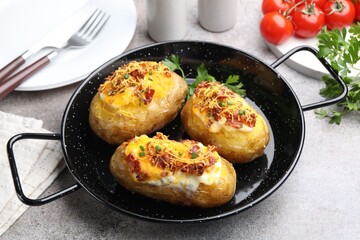 Tasty stuffed baked potatoes in baking dish served on grey table, closeup