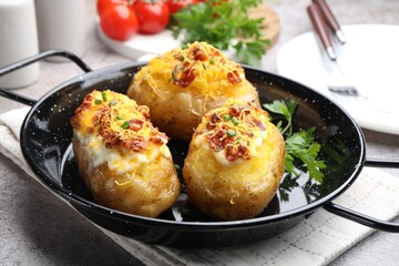 Tasty stuffed baked potatoes in baking dish on grey table, closeup