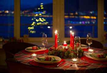 beautifully decorated Christmas table with candles and glasses near the Christmas tree