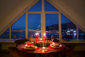 beautifully decorated Christmas table with candles and glasses near the Christmas tree