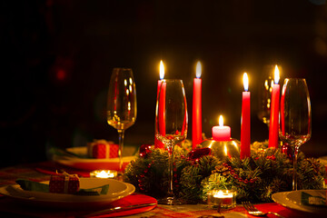 beautifully decorated Christmas table with candles and glasses near the Christmas tree