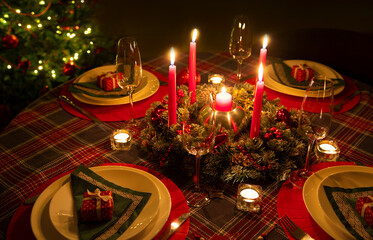 beautifully decorated Christmas table with candles and glasses near the Christmas tree