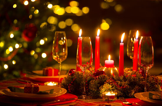 beautifully decorated Christmas table with candles and glasses near the Christmas tree