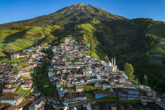 Aerial view of a vibrant village cascading down verdant slopes towards a majestic mountain peak, Nepal Van Java, Magelang, Jawa Tengah, Indonesia.